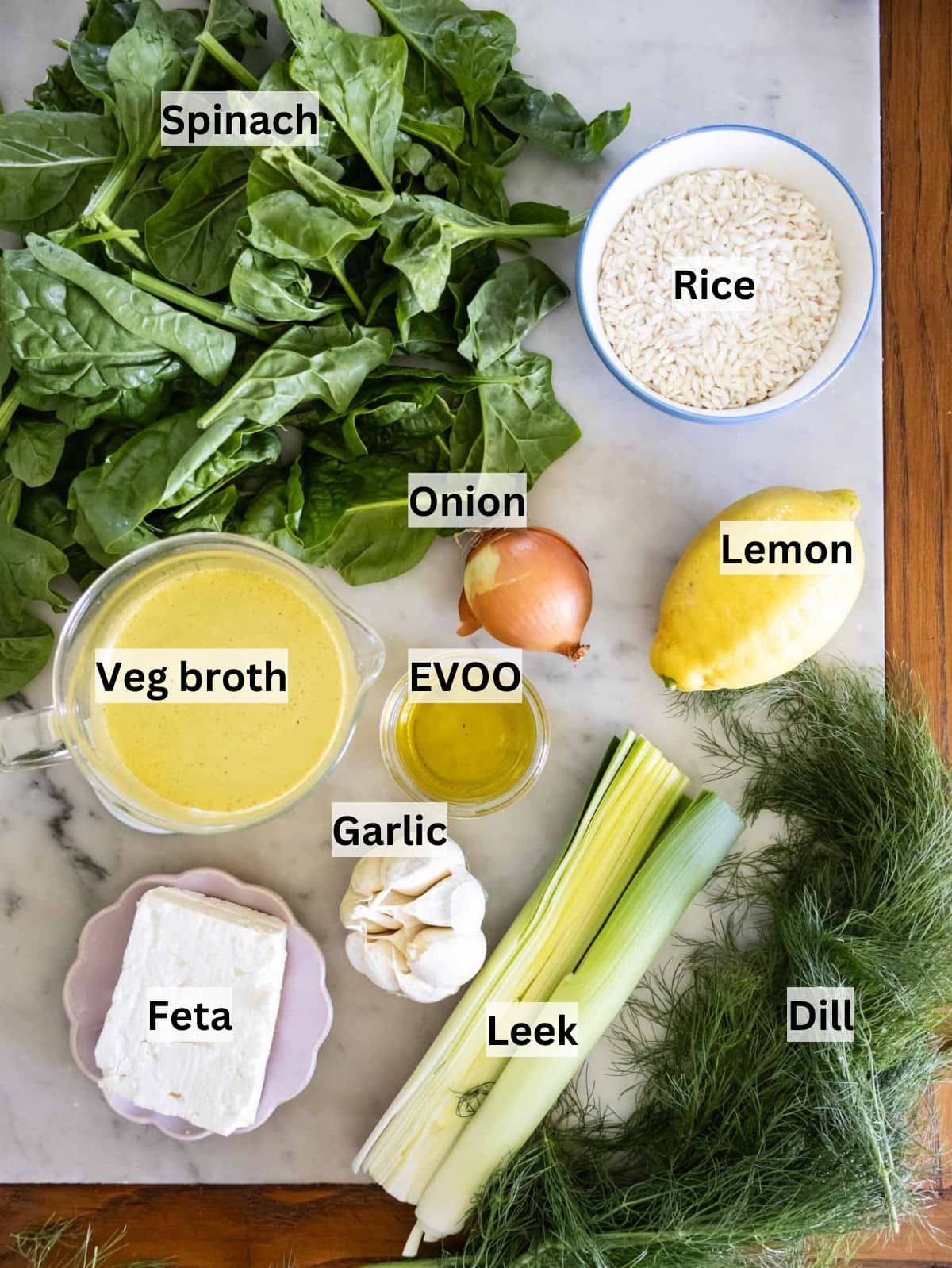 Spanakorizo ingredients laid out olive oil spinach rice dill lemon and feta for Greek recipe.