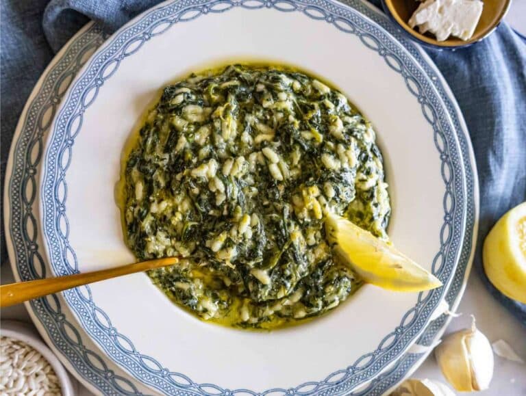 Spanakorizo served on a white and blue plate with lemon and olive oil.