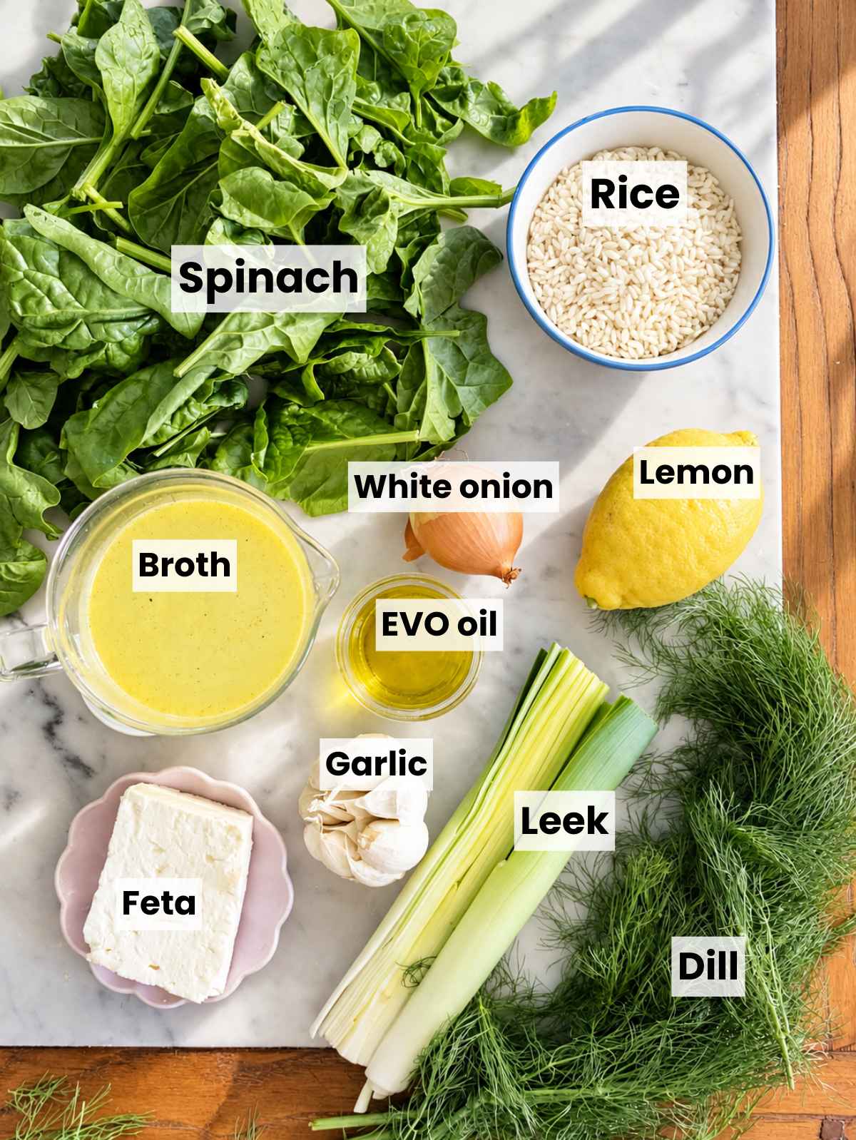 Spinach, rice, feta, lemon, dill, and aromatics on white marble.