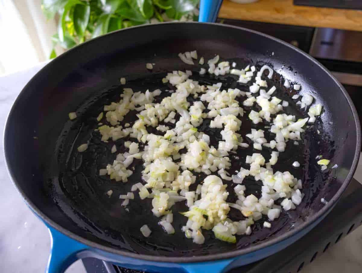 Step 1 Sautéing onion and garlic in skillet for flavor base of creamy butter bean sauce.
