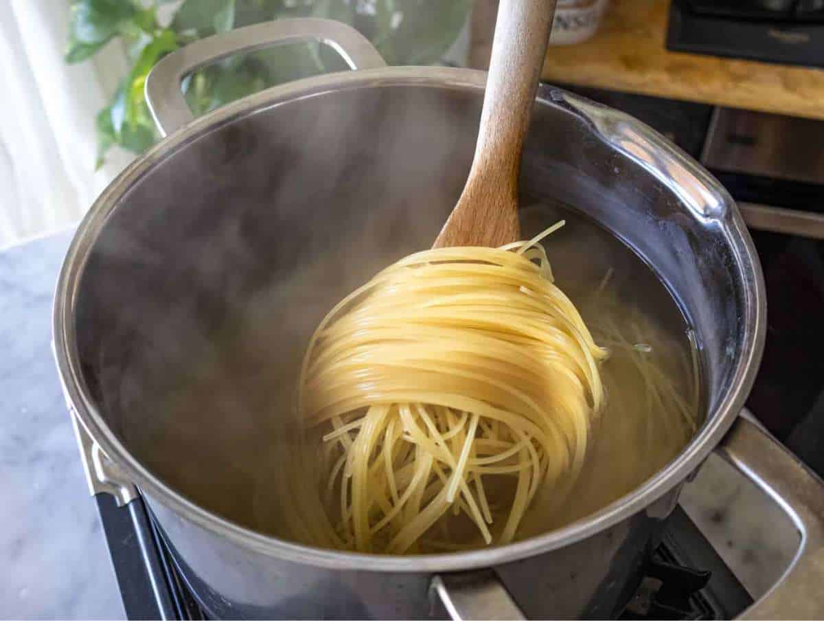 Step 3 Angel hair pasta boiling in salted water inside a large stainless steel pot.