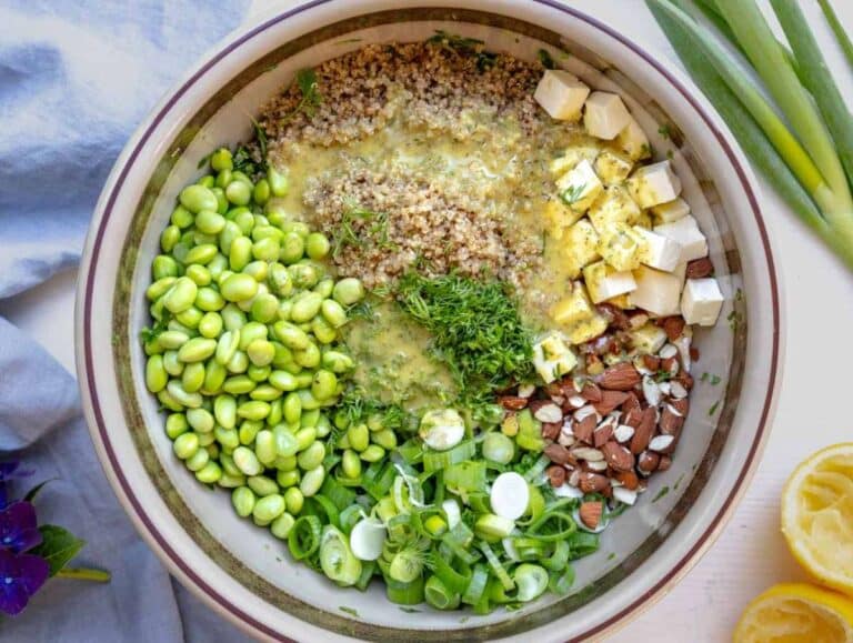 Toasted almonds, chopped dill, scallions, and cooked edamame in the bowl with the kale