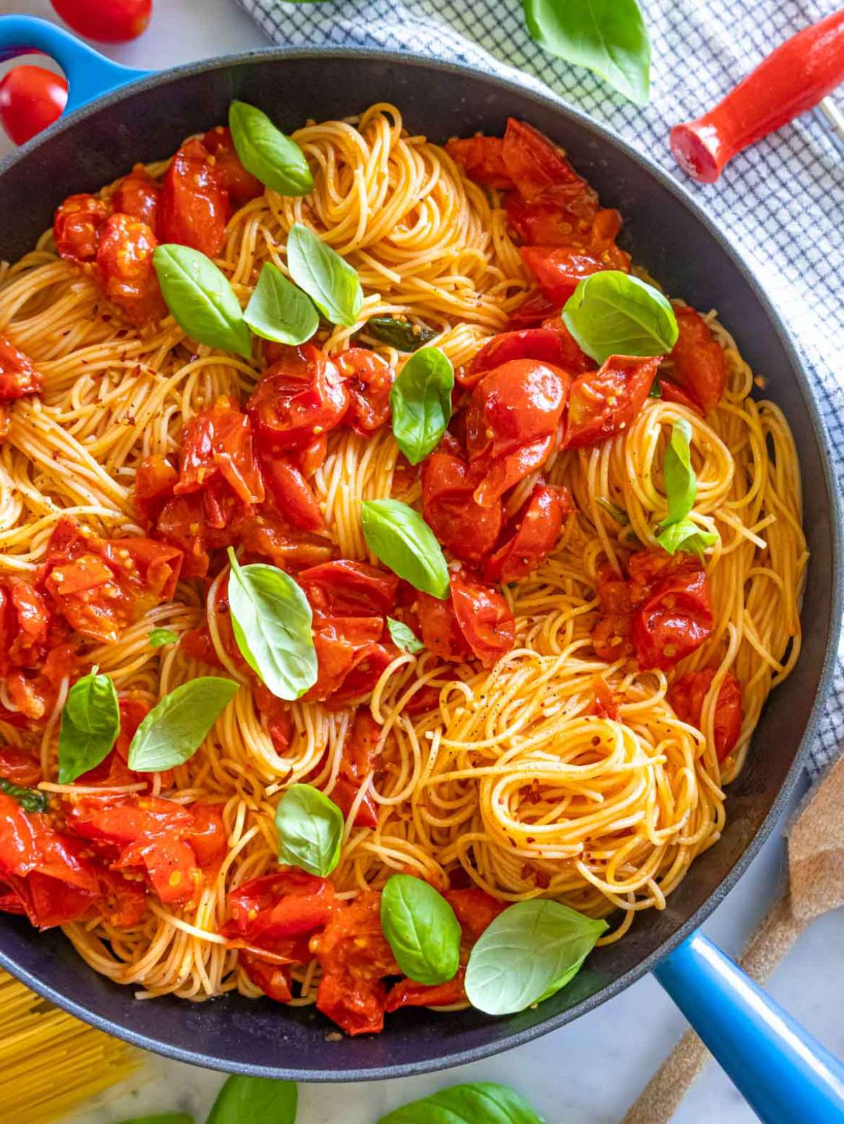 Angel hair pasta with fresh tomatoes, parmesan, and basil served in a blue skillet.