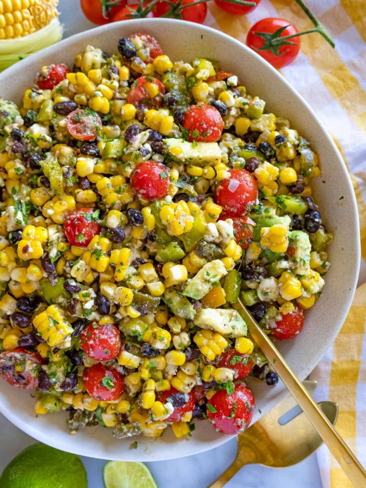 Top-down view of corn salad with avocado, black beans, cherry tomatoes, bell peppers, and crumbled feta in a large serving bowl—perfect for a healthy summer side dish.