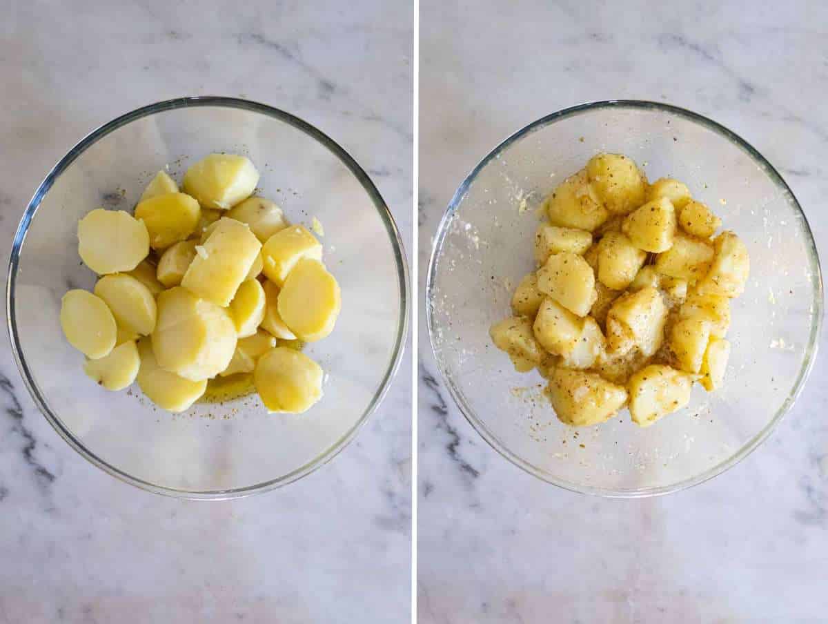 Warm potato chunks being gently mixed with oregano vinaigrette in a large mixing bowl.