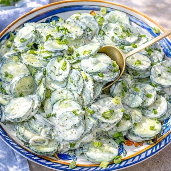 A Greek yogurt cucumber salad recipe with a golden spoon on a plate.