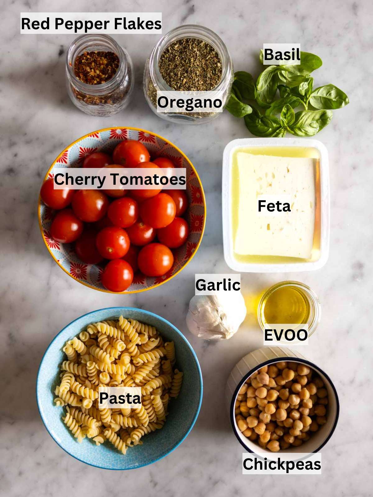 All ingredients for baked feta pasta arranged neatly including feta cherry tomatoes and chickpeas.
