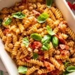 Baked feta pasta recipe served with basil lemon zest and olive oil on rustic table.