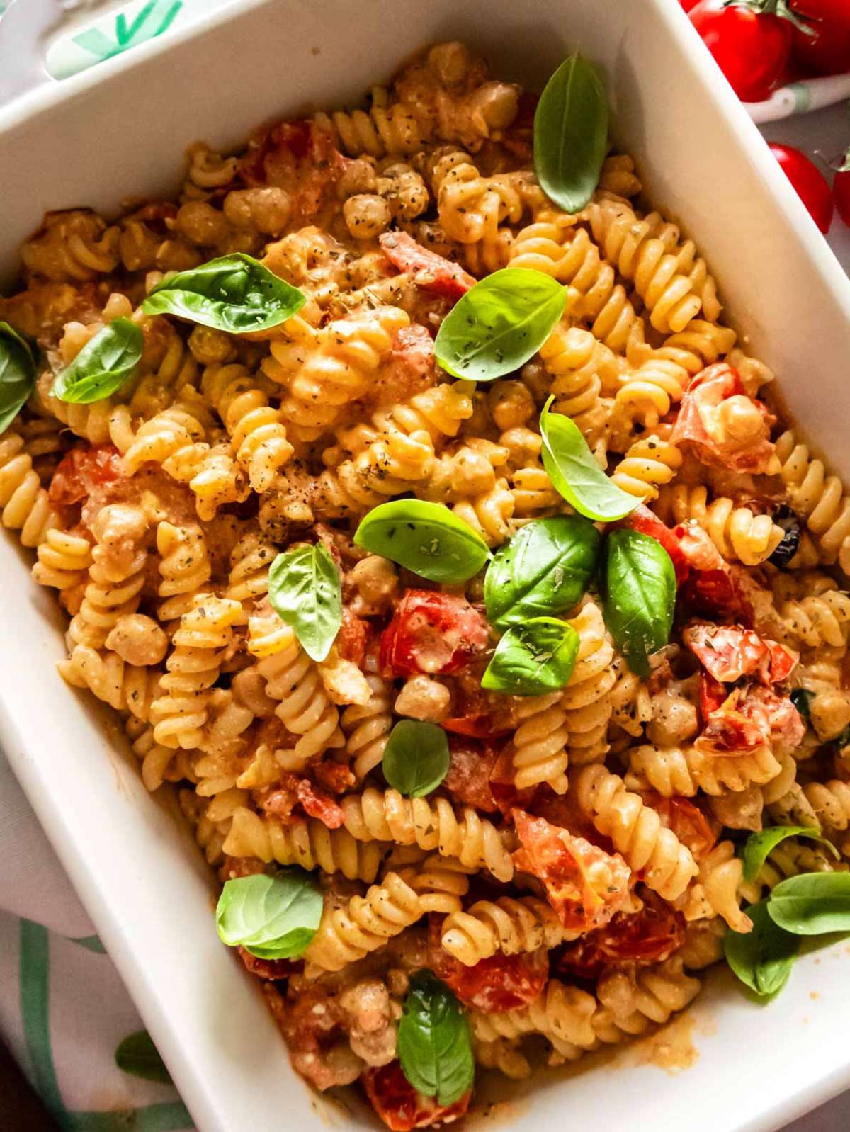 Baked feta pasta with chickpeas and cherry tomatoes in white baking dish.