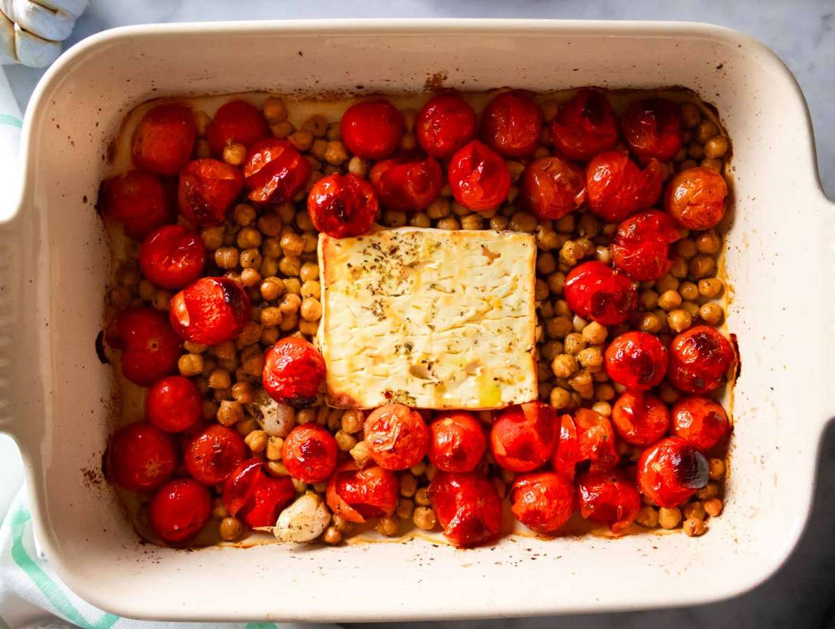 Cherry tomatoes chickpeas and feta arranged in baking dish before roasting.