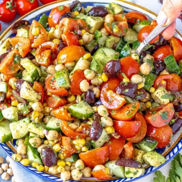 Chickpea cucumber salad served on a blue platter with avocado and fresh parsley.