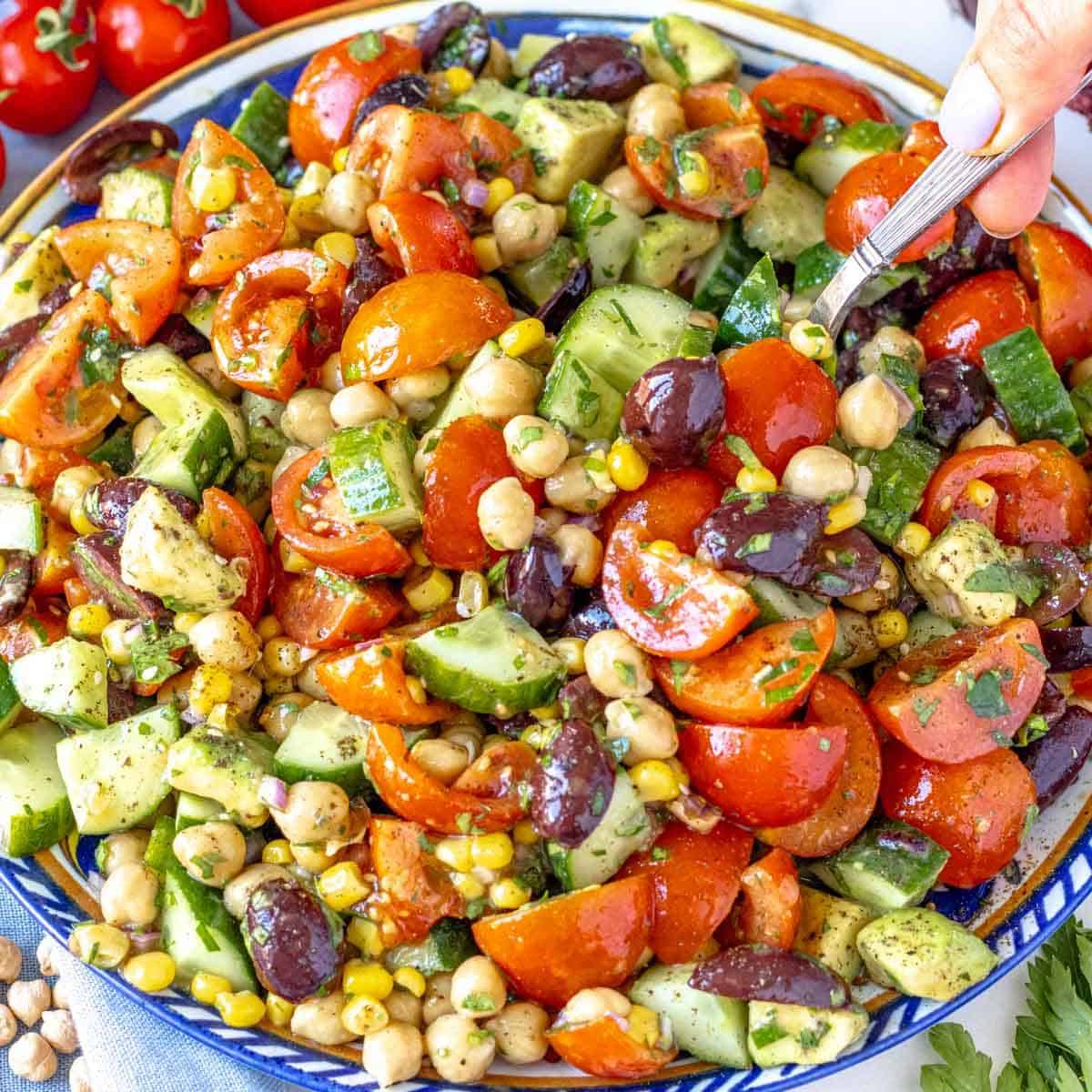 Chickpea cucumber salad served on a blue platter with avocado and fresh parsley.