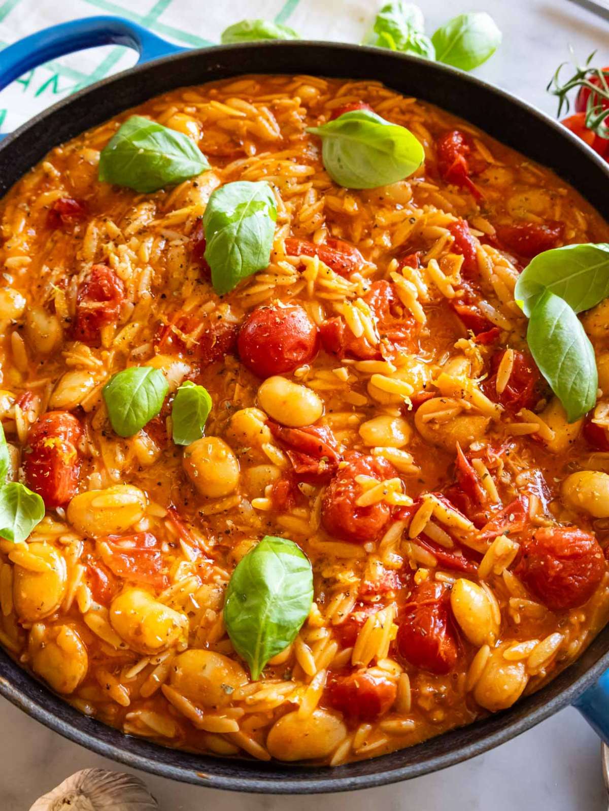 Close-up of cherry tomato orzo with butter beans lemon and fresh basil.