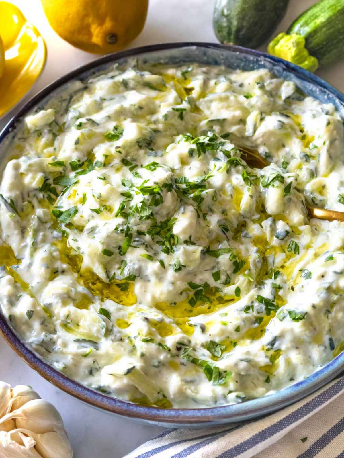 Close up of creamy zucchini tzatziki dip with herbs and olive oil drizzle.