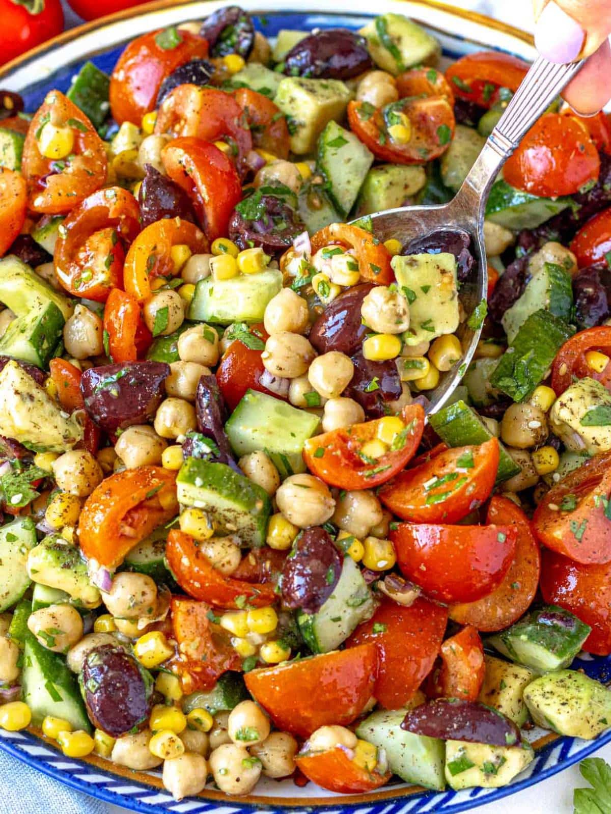 Colorful chickpea cucumber salad with tomatoes olives cucumber and parsley.
