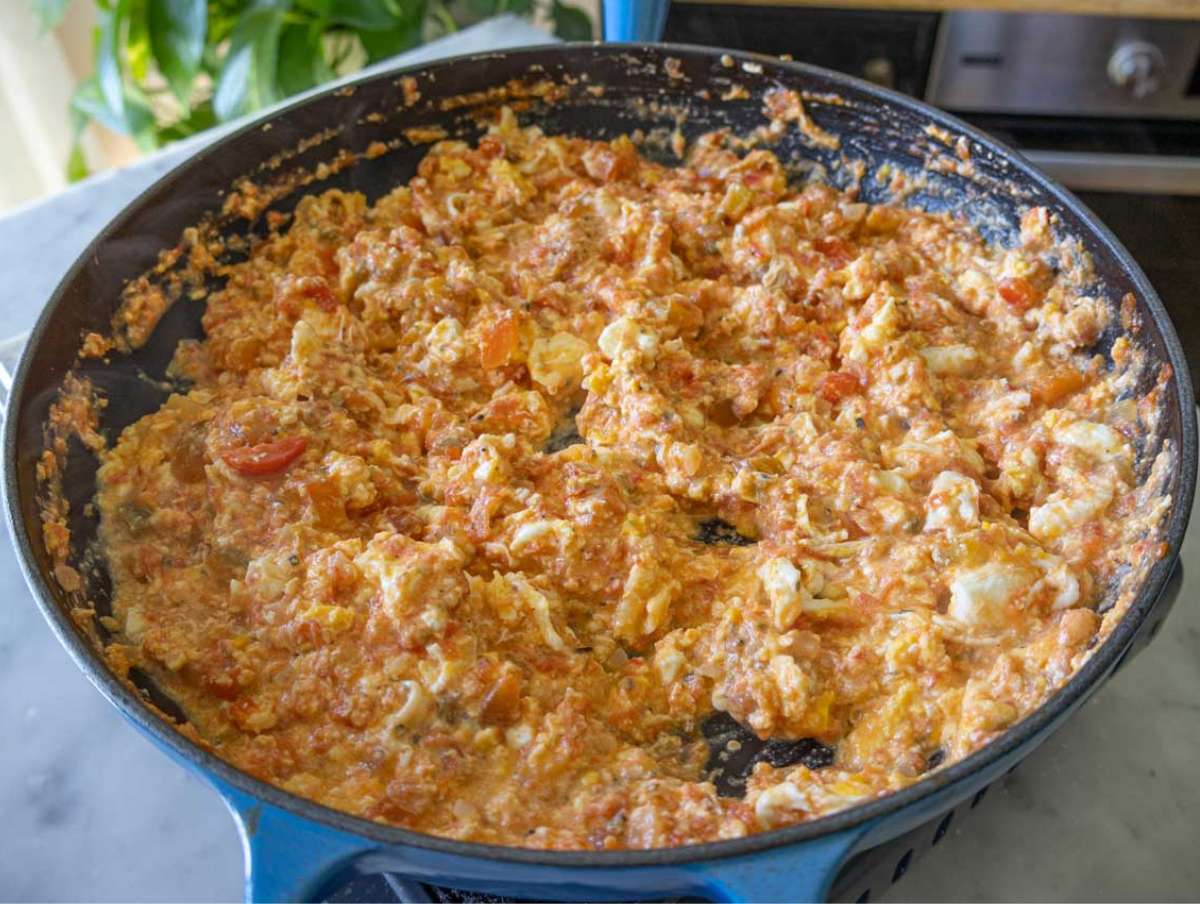 Cracked eggs gently stirred into tomato mixture in skillet.