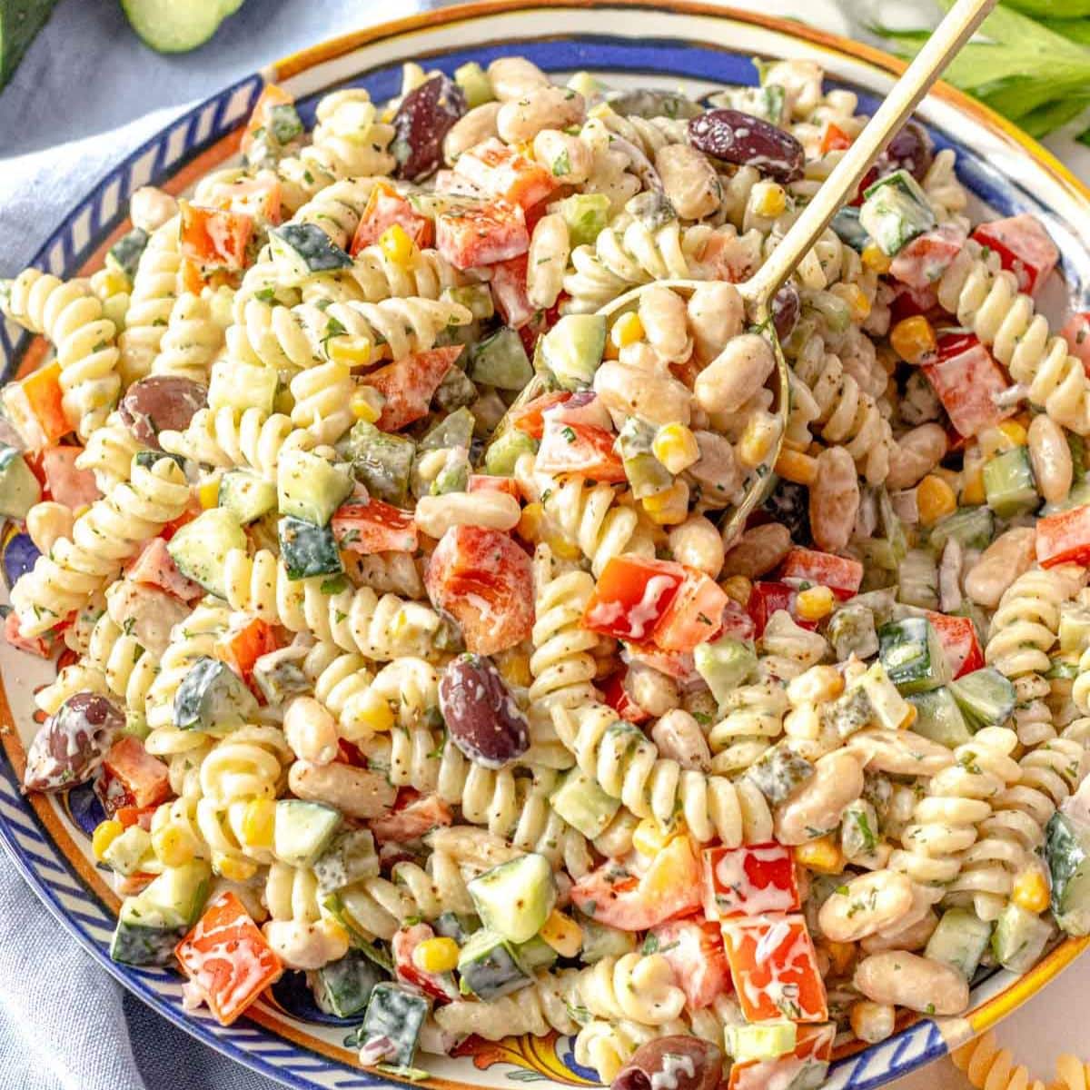Creamy Greek yogurt pasta salad with beans and vegetables in a serving bowl.
