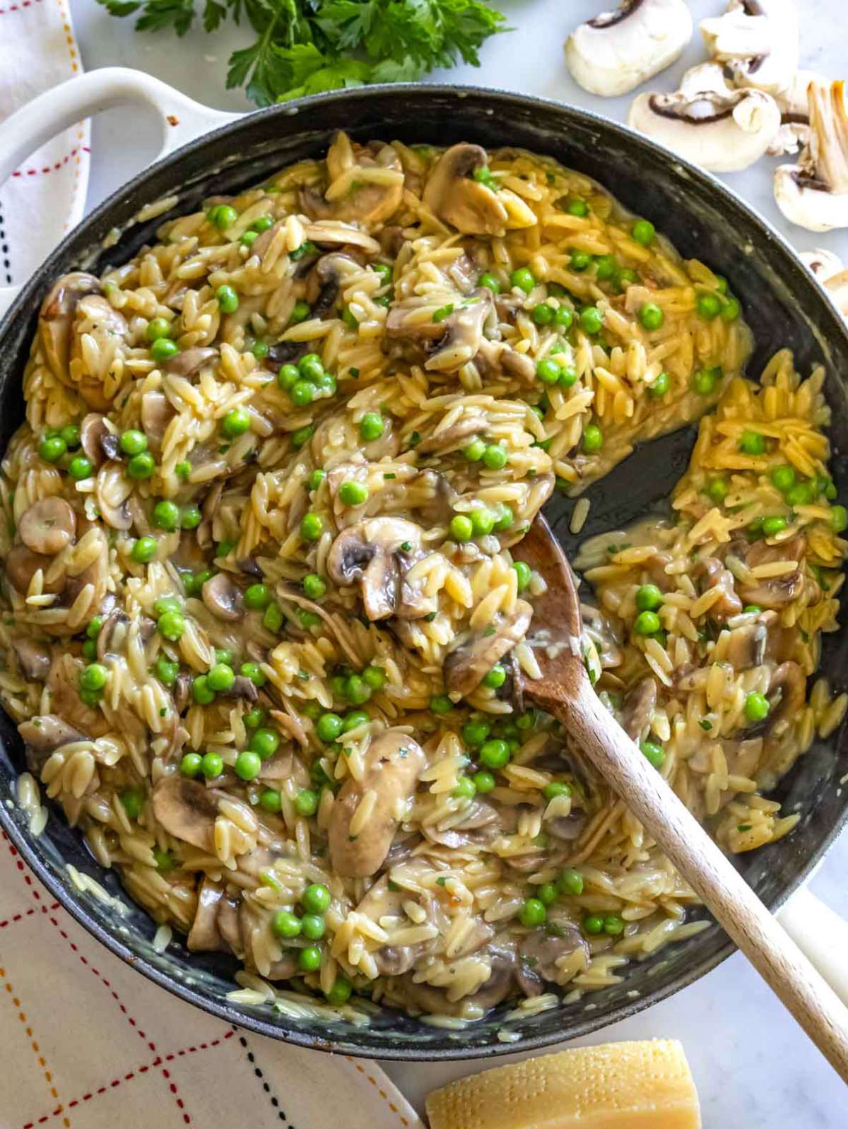 Creamy mushroom orzo recipe with peas in a white bowl with parsley garnish.