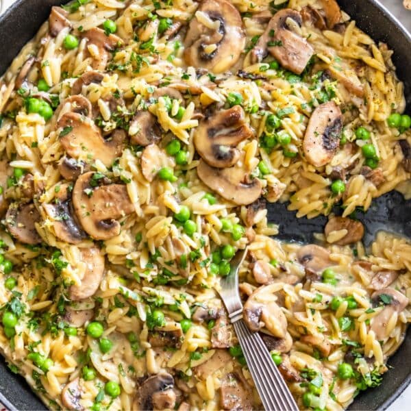 Creamy mushroom orzo with browned mushrooms, peas, parsley, and Parmesan in natural window light.