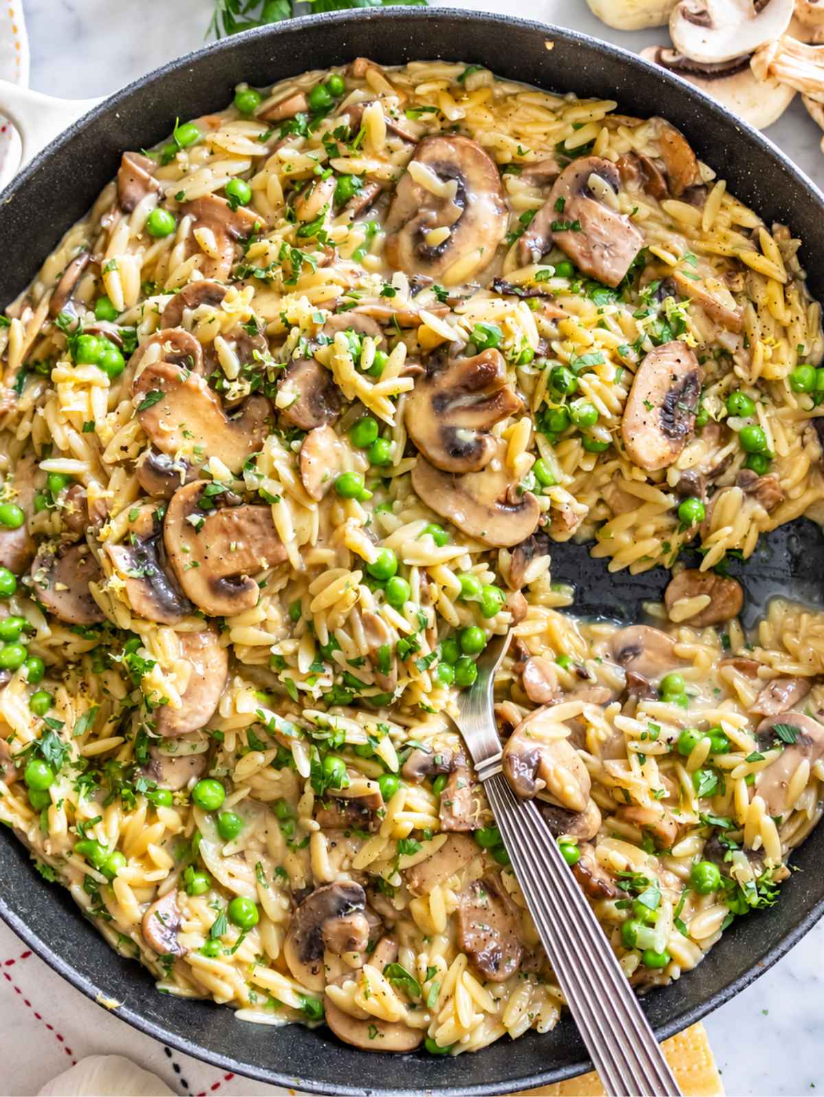 Creamy mushroom orzo with sauteed mushrooms, green peas, Parmesan, and fresh parsley.