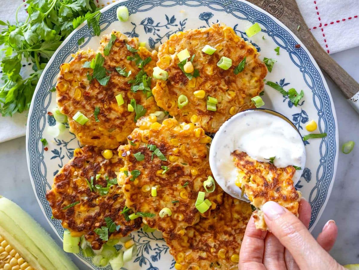 Crispy golden corn fritters with feta and mint on a white plate.