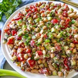 High protein bean salad in a large bowl with lemon wedges and parsley garnish.