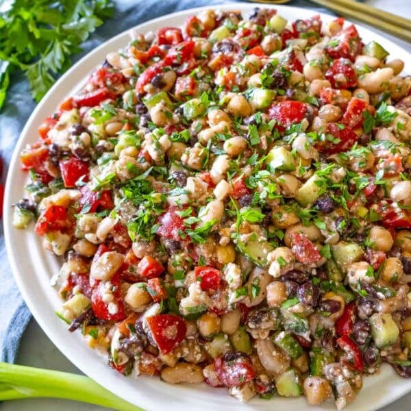 High protein bean salad in a large bowl with lemon wedges and parsley garnish.