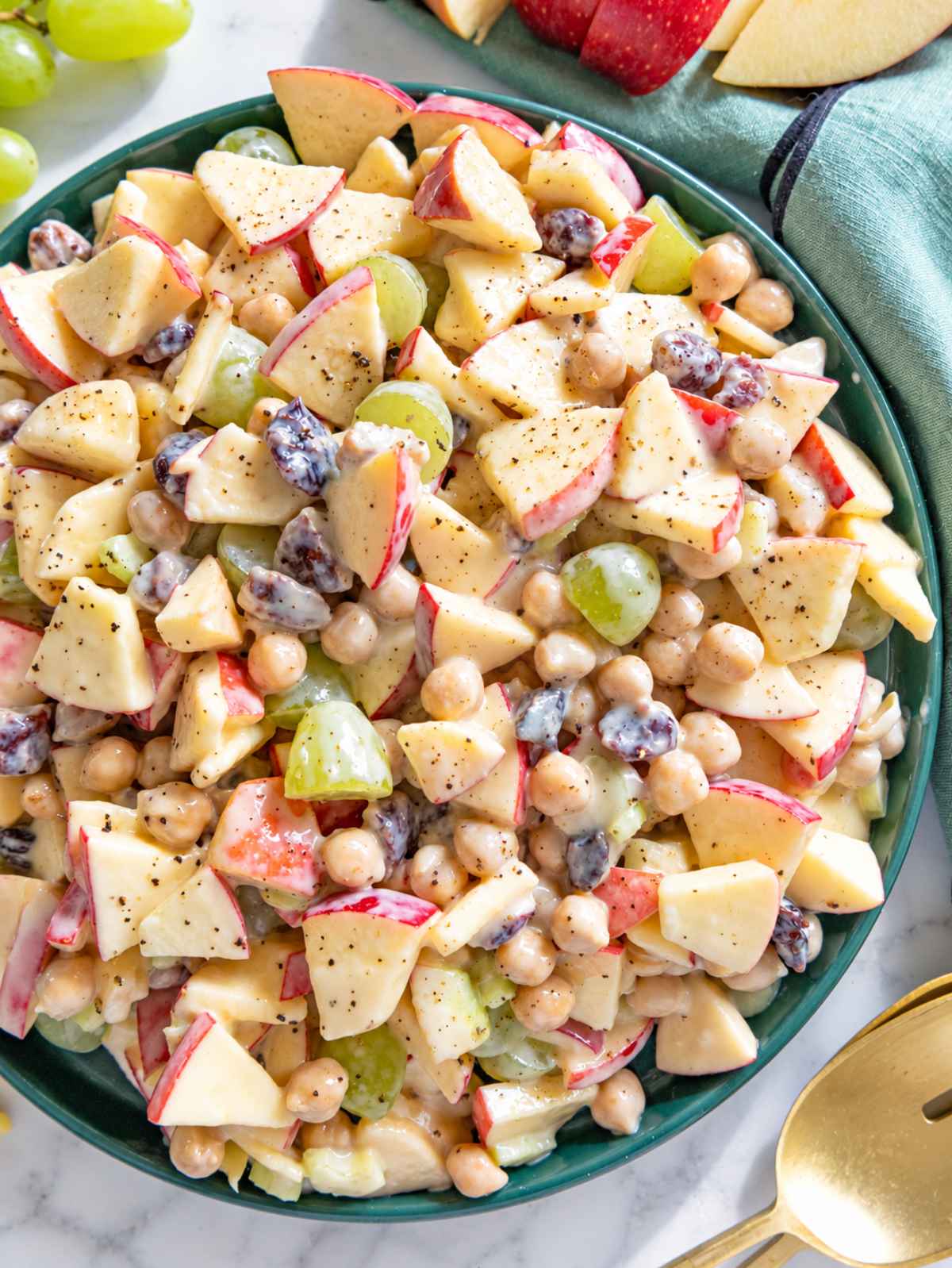 Flat lay of glossy apple chickpea salad coated in creamy yogurt dressing with spoon.