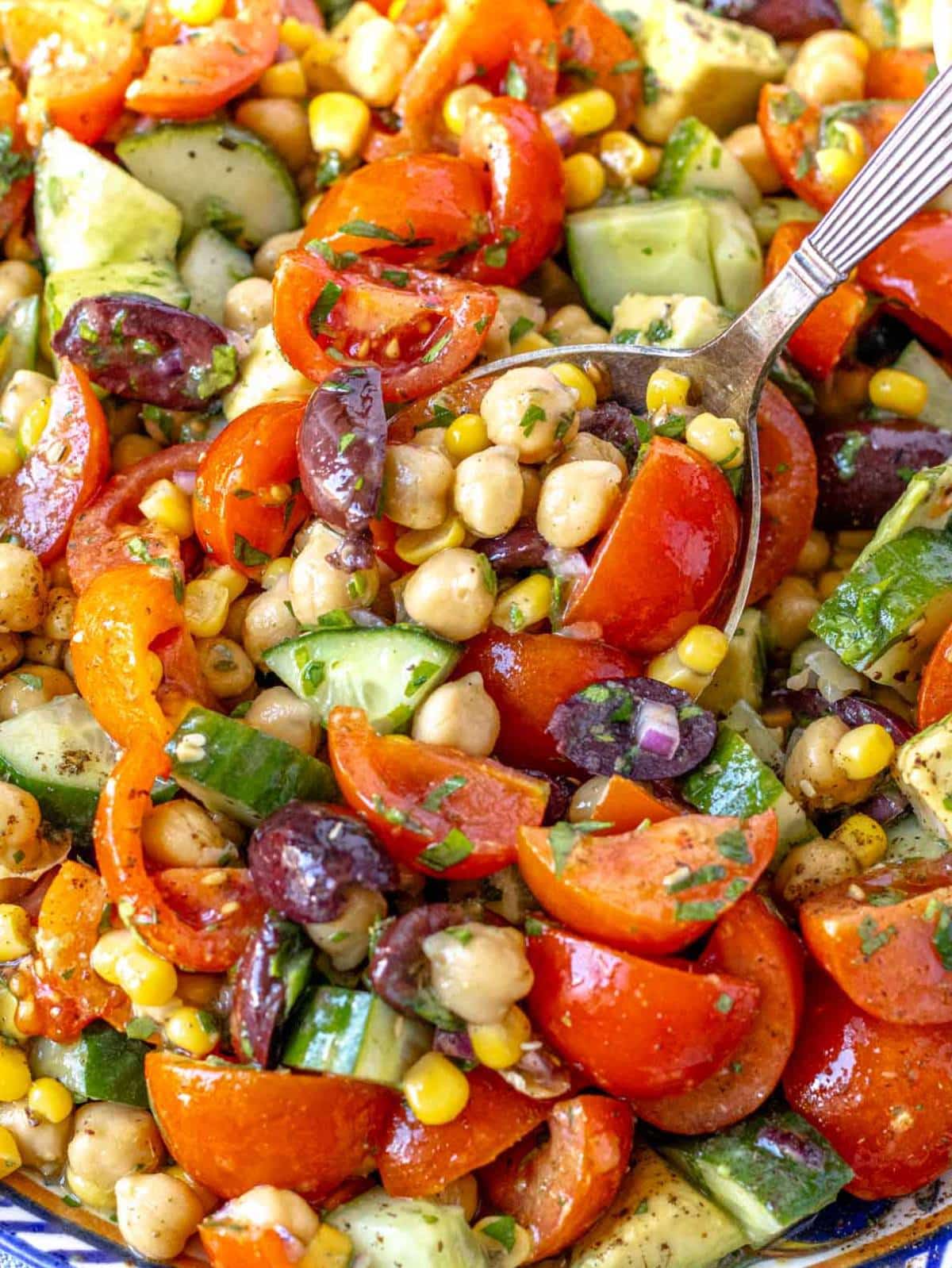 Fresh chickpea cucumber salad close up with avocado and Mediterranean dressing.