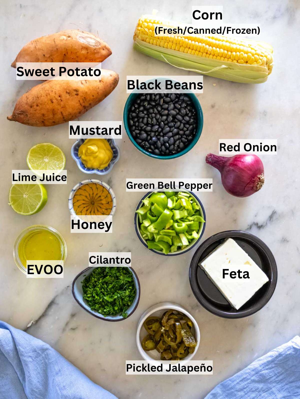 Ingredients for black bean corn salad with cilantro and lime arranged on a marble table.