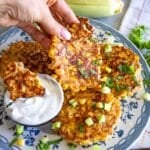 Louise holding a corn fritter while another is dipped in yogurt on a serving plate