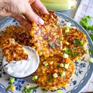 Louise holding a corn fritter while another is dipped in yogurt on a serving plate