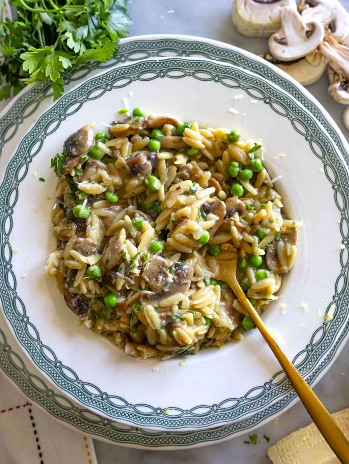 Mushroom orzo served in green and white plate with lemon zest.