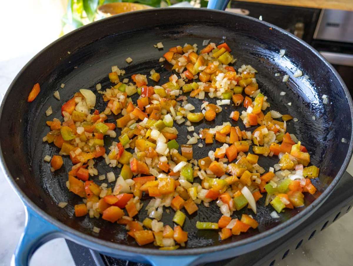 Onion and bell pepper cooking in olive oil in a skillet.