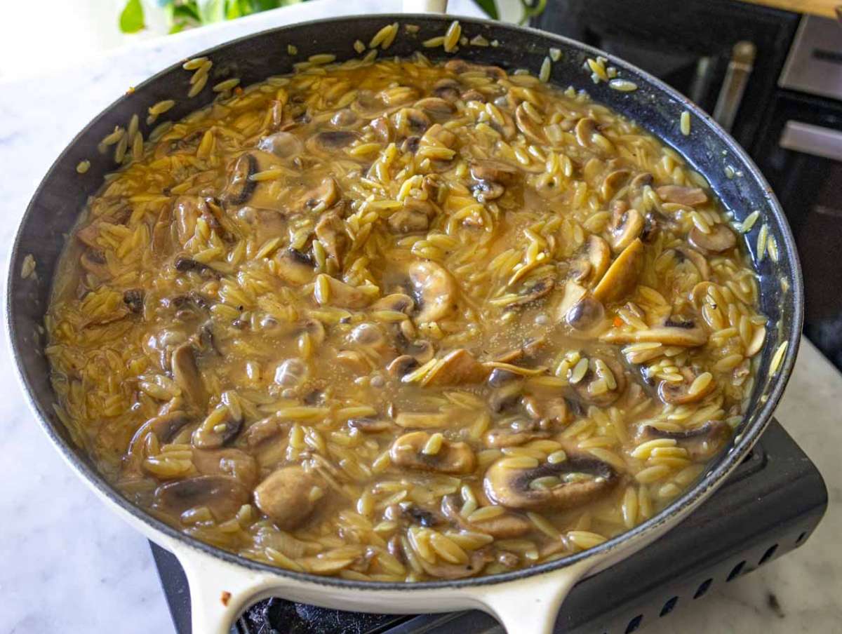 Orzo simmering in vegetable broth with mushrooms in a one pot dinner.