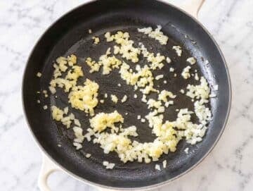 Step 1 Chopped onion and garlic sautéing in olive oil in a large skillet.