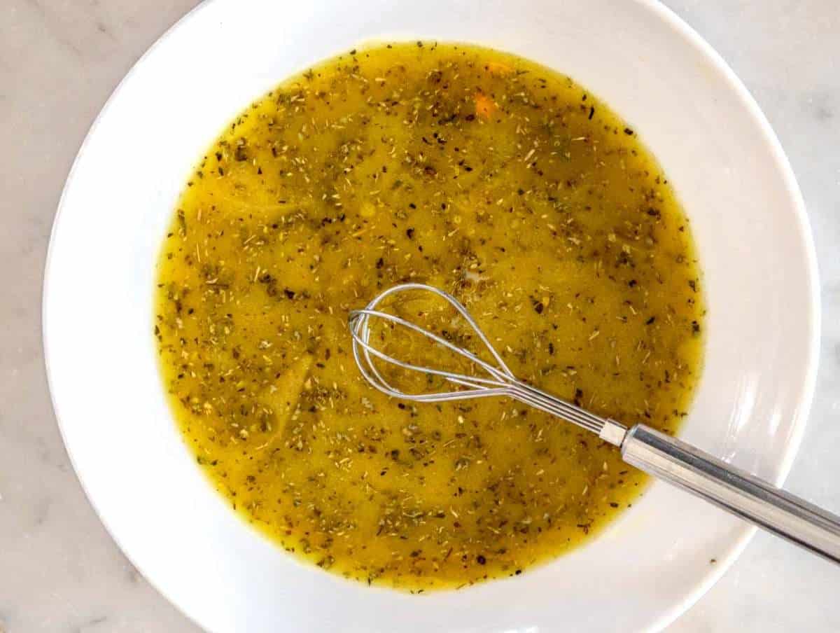 Step 1 Whisking olive oil vinegar mustard honey and oregano for chickpea cucumber salad dressing.