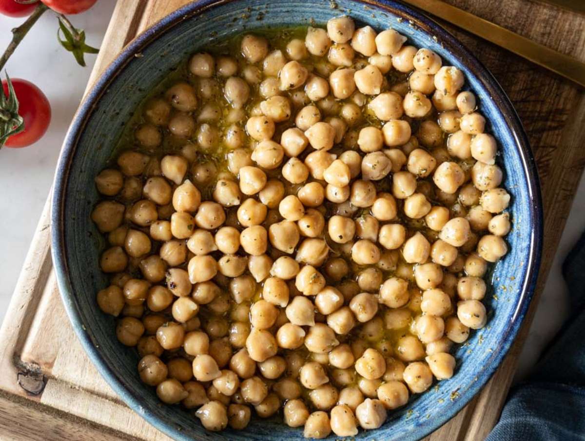 Step 2 Chickpeas tossed in lemon oregano dressing marinating for more flavor in a blue bowl.