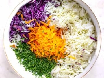 Step 2 Mixing shredded cabbage, grated carrots, and chopped parsley in a large bowl.