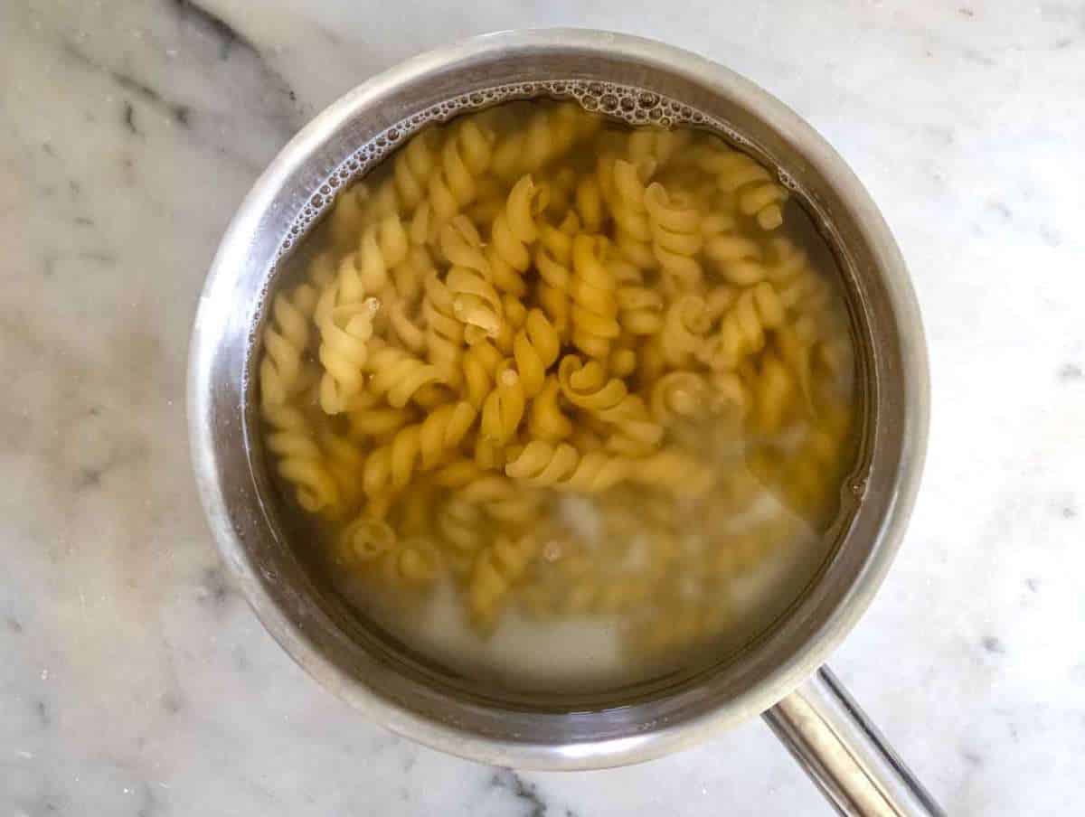 Step 2 Pasta boiling in a large pot of salted water on a stovetop.