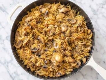Step 3 Orzo simmering with browned mushrooms and vegetable broth in the skillet.