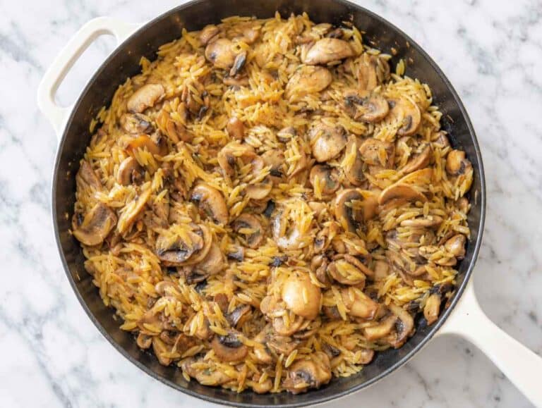 Step 3 Orzo simmering with browned mushrooms and vegetable broth in the skillet.