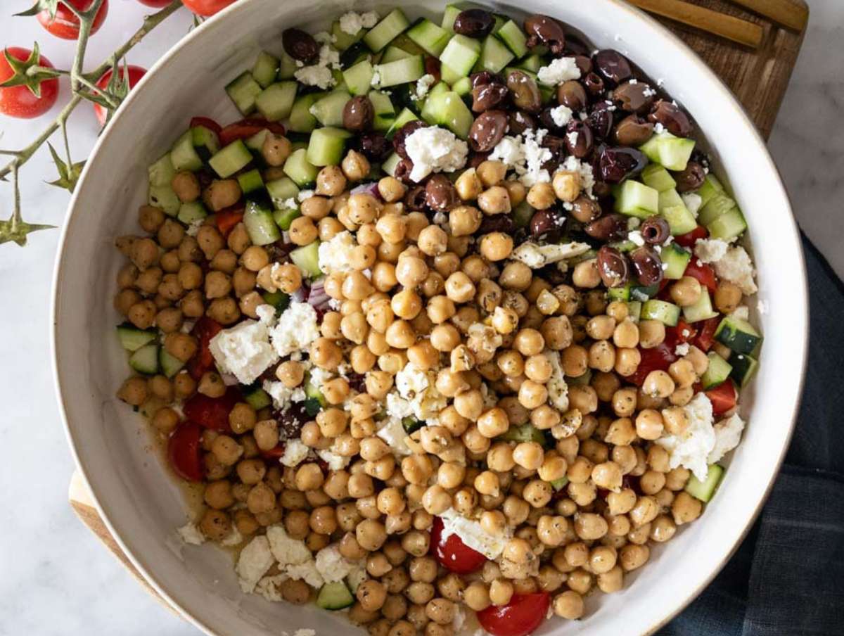 Step 4 Chopped tomatoes cucumber onion olives and feta in a bowl ready to mix with chickpeas.