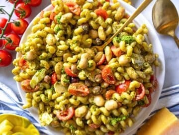 Step 4 pesto pasta salad with marinated butter beans served on a white platter.