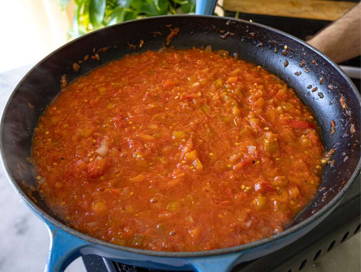 Tomato sauce simmering in a pan until thickened for strapatsada.