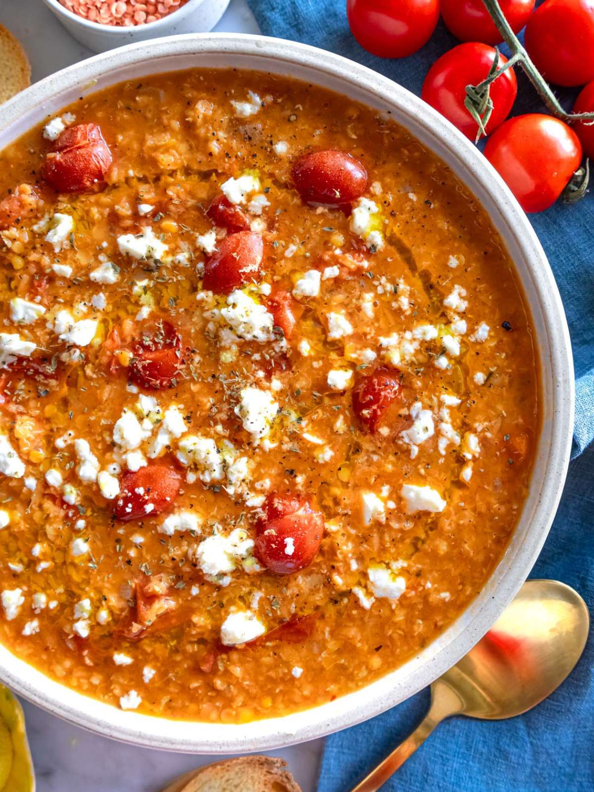 Top down photo of tomato lentil soup served in bowls with crusty bread.