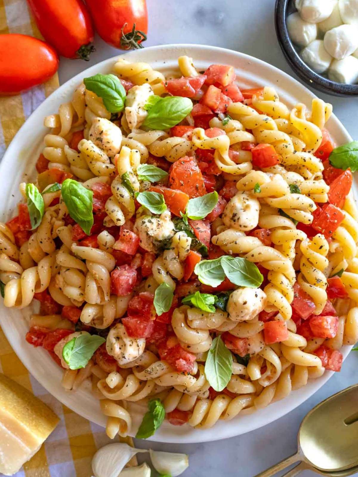 Top-down view of bruschetta pasta with fresh basil mozzarella and tomatoes on a rustic table.