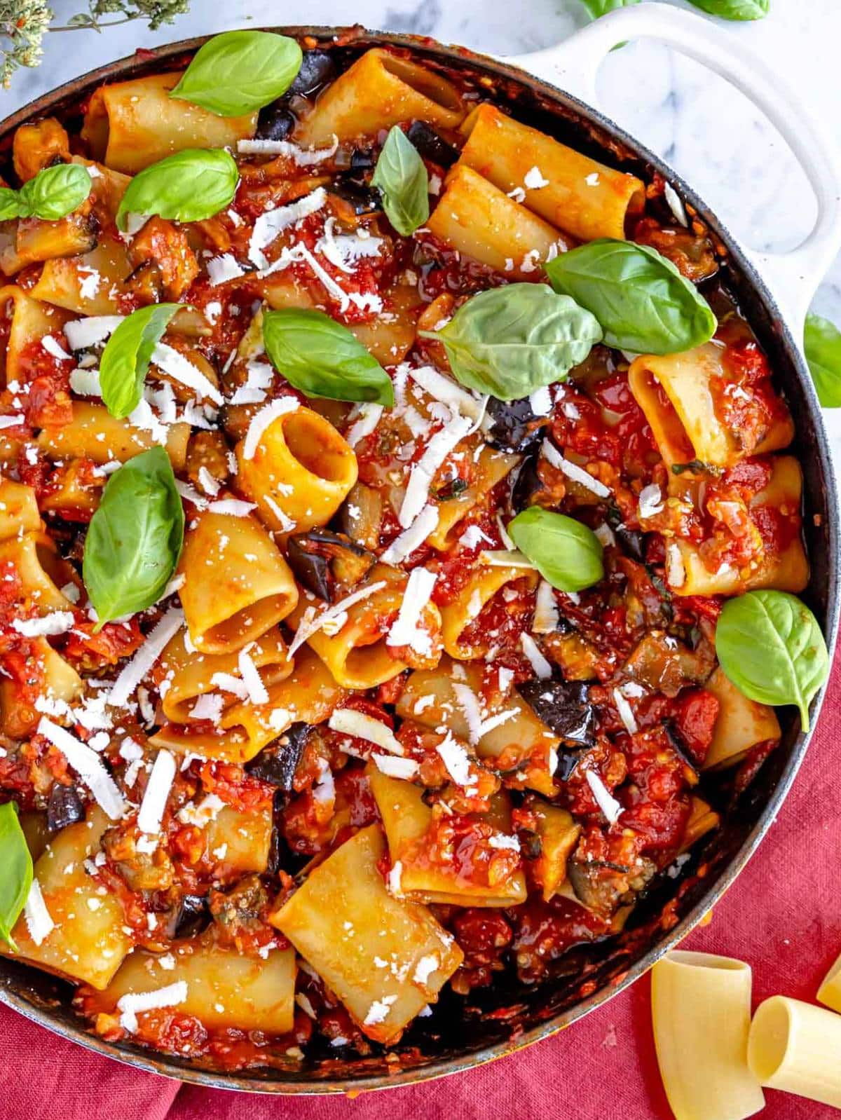 Top down view of pasta alla Norma in a skillet with ricotta salata.