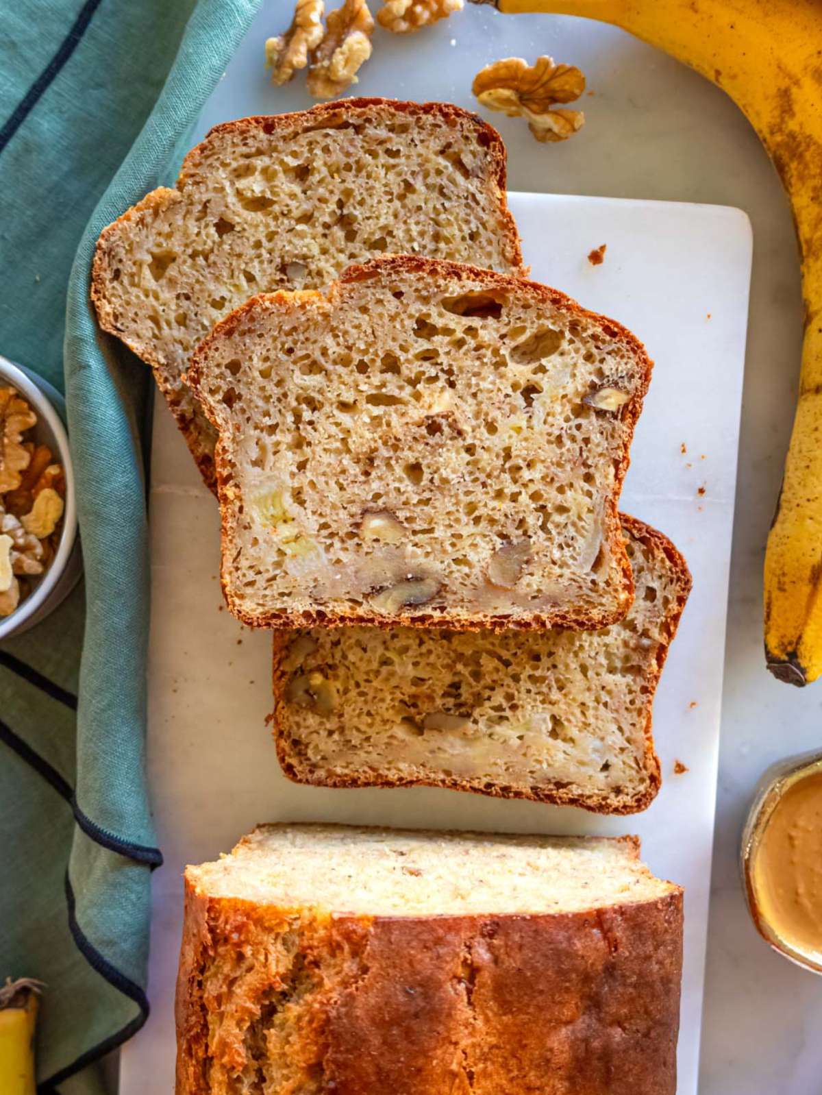 Top down view of sliced freshly baked protein banana bread loaf on marble cutting board.