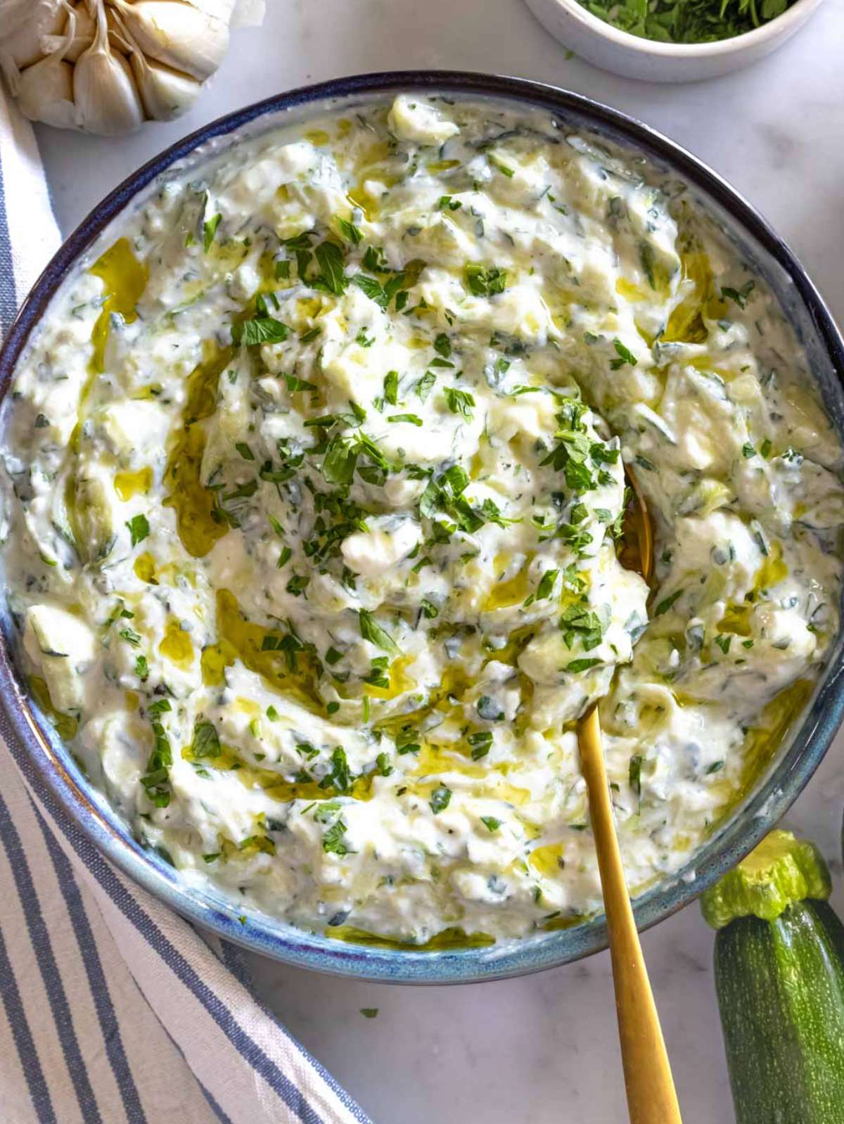 Top down view of zucchini tzatziki served with pita bread and veggie sticks.